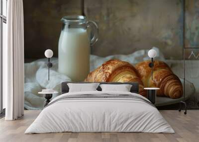 Two golden brown croissants are presented on a plate, accompanied by a glass pitcher of milk, creating a tempting breakfast scene Wall mural