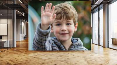 Young boy with blonde hair smiling while waving hello Wall mural