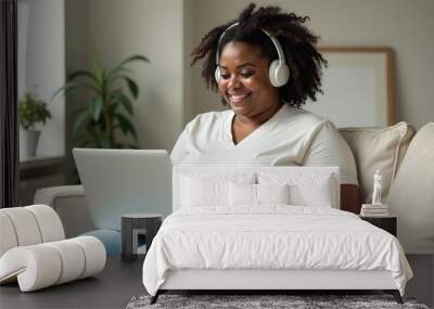 A large African American woman is sitting on the couch and working online on a laptop Wall mural