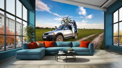 Couple taking off their bicycles from roof rack Wall mural