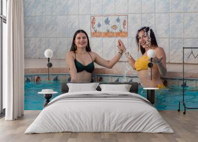 dos hermosas chicas calientes en bikini disfrutando en la piscina Wall mural