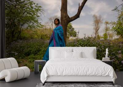 Girl in blue saree standing with a smile on her face Wall mural