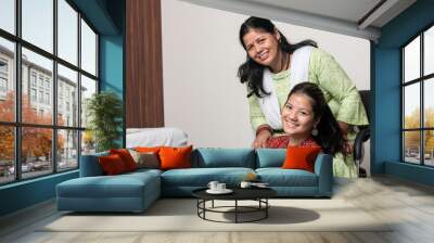 Portrait of a young indian girl having fun with her mother, posing towards the camera with her mother. Wall mural