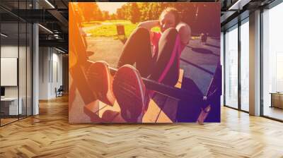 Abs bench wooden outdoors. Girl in pink sportswear doing exercises at street workout place in summer morning. Healthy lifestyle sport concept. Wall mural