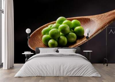 Close up of pea on wooden spoon with dark background Wall mural