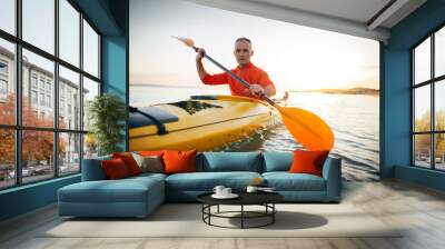 Active senior man paddling the kayak on a sunset sea Wall mural