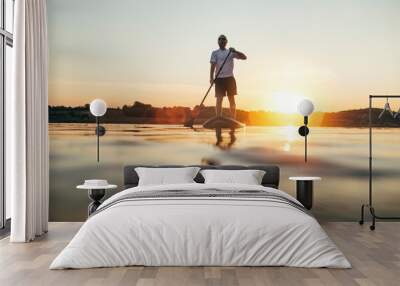 Man paddleboarding on the lake at sunset Wall mural