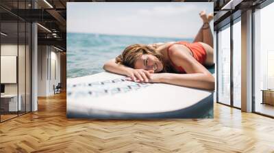 Smiling woman enjoys sunbathing on paddle board Wall mural