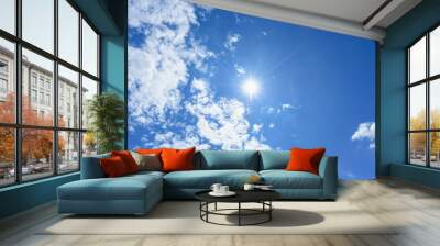 Blue sky with clouds and sun reflection. looking up view. Wall mural