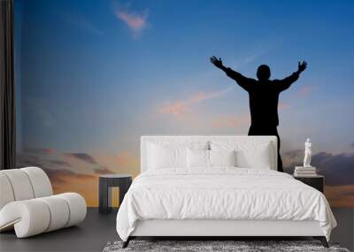 Silhouette of man raised hands at sunset Wall mural