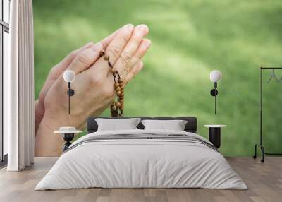 Woman hands praying with a rosary Wall mural