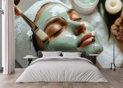 Woman receiving facial treatment with green clay mask. Wall mural