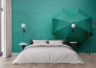 A green umbrella resting on a teal surface in soft light Wall mural