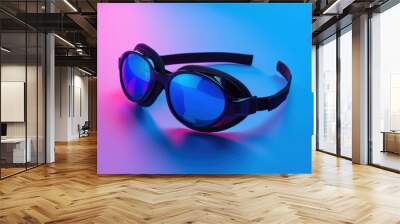 Stylish black swimming goggles with reflective blue lenses on colorful background Wall mural