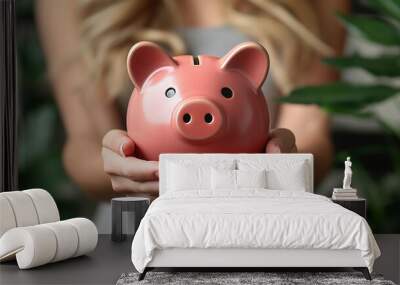 A hand carefully places a coin into a brightly colored piggy bank, symbolizing savings, financial growth, and responsible money management, while highlighting the importance of building wealth over ti Wall mural