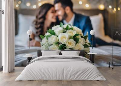 Bouquet of white roses on bed, young couple in love blurred in background Wall mural