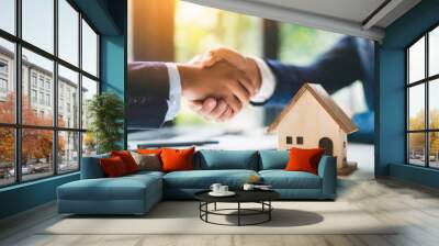 Business deal handshake over blurred wooden house on table, symbolizing agreement, partnership, real estate, success Wall mural