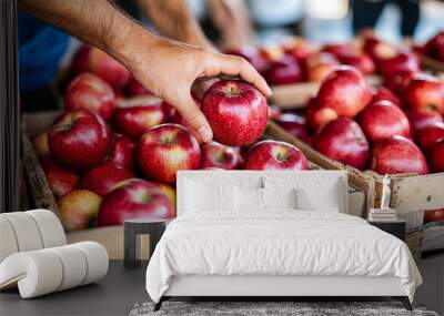 hand reaching for a shiny apple amidst a collection of wooden crates filled with ripe fruit. The image captures the temptation of choice and abundance, set against a rustic backdrop Wall mural