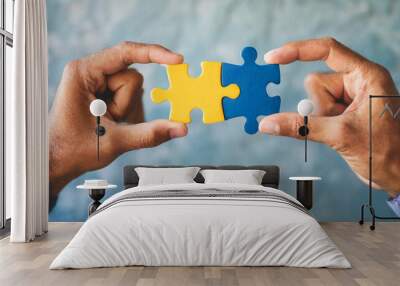 Two hands each holding a jigsaw puzzle piece, aligning them against a blank wall, symbolizing connection, teamwork, and problem-solving, emphasizing unity and collaboration in achieving a common goal Wall mural