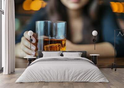 woman gazes down while holding a glass of whiskey, symbolizing emotional turmoil, depression, and the struggles of coping with inner conflict and life's hardships Wall mural