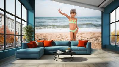 Little cute girl shows thumb up while swimming in the sea during the weekend on a warm summer day. Concept of happy kids on vacation. Copyspace Wall mural