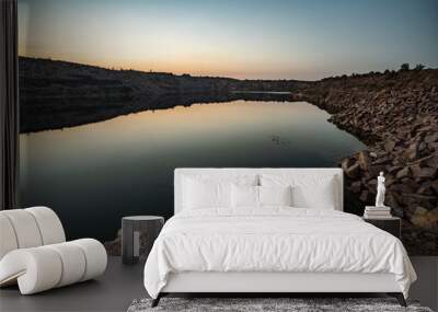 Old flooded stone quarry surrounded by stone waste from a mine work against a beautiful night sky Wall mural