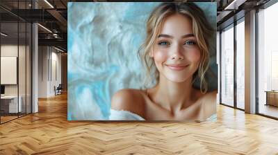 Young woman with a serene smile poses against a textured blue backdrop in a bright setting Wall mural