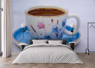 white and blue Cup of Turkish Coffee on a blue plate and gold plated tea spoon , flowers and butterfly on the ceramic mug  Wall mural