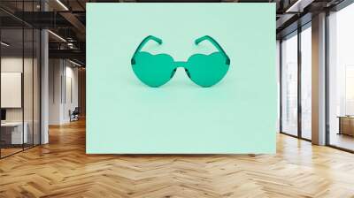 Minimal style fashion photography with heart shaped glasses on green paper background. Light green modern sunglasses.  Trendly summer concept. Copy space. Wall mural