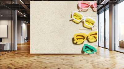 Stylish colored sunglasses on sand background at sunlight, summer fashion eyeglasses with colors glass. Summer sale concept in optical store. Top view lifestyle aesthetic photo, copy space Wall mural