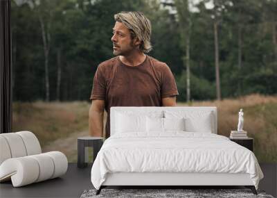 Blonde man with a stubble beard in a brown t-shirt on a sandy pa Wall mural