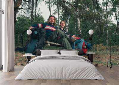 Two male backpackers resting on bench in forest in spring. Wall mural