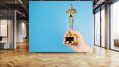 Oscar statue, award in hand on blue background,copy space Wall mural