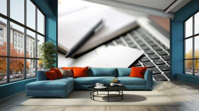 A business card and a paper notebook with a pen on a laptop keyboard. Shallow depth of field. Wall mural