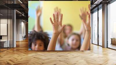 Group of school children raising their hands in a classroom. Selective focus. Wall mural