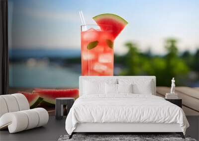 Refreshing summer drink with watermelon and ice in a glass on a wooden table on beach background Wall mural