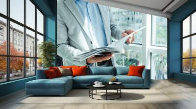 businessman in a business suit reads a magazine near the window with a plant Wall mural