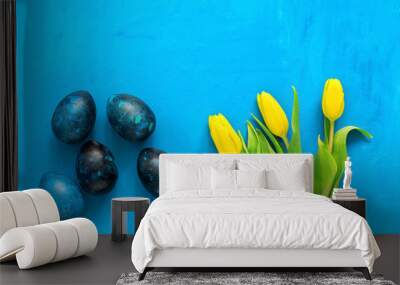 Easter eggs and yellow tulip on a blue painted background. Beautiful greeting card. Top view, flat lay. Wall mural