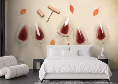 Flat lay red wine in glasses decorated with autumn leaves on a concrete beige background. Top view, wide. Wall mural