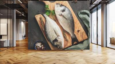 Fresh raw dorado fish, lemon and spices on a wooden cutting board, dark rustic background. Top view, flat lay, toned. Wall mural