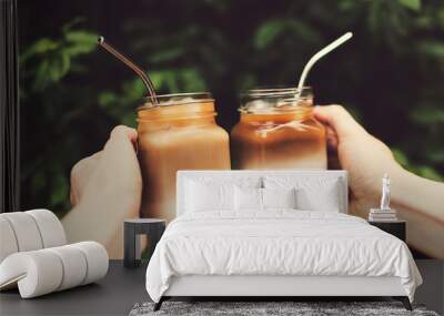 Clink of two glass jars of ice coffee in woman and man hands. Wall mural