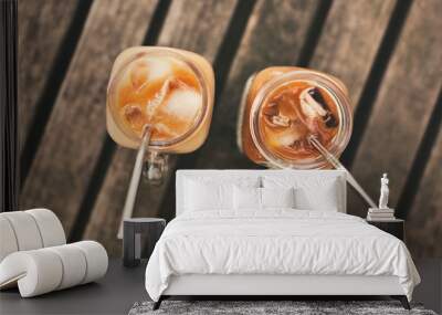 Two glass jars of ice coffee on wood table with metal straws. Wall mural