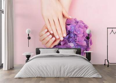 Woman hands with perfect pastel manicure holding hydrengea flower. Gentle pink nail polish, beautiful shape. Nail care concept. Wall mural