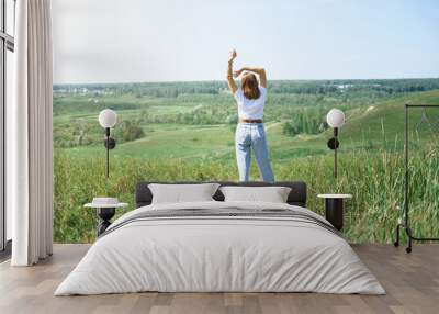  field summer landscape, happy young model. freedom and relaxation concept in summer and spring. woman wearing casual clothes and enjoying travel. rear view Wall mural