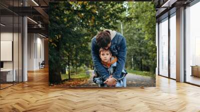 Caucasian man hugging his son in autumn park supporting sad boy Wall mural