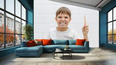 cute 8 years old boy brushing teeth with bamboo tooth brush in bathroom. Image with selective focus Wall mural