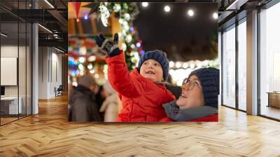 cute baby girl on mother hands outdoors at christmas market Wall mural