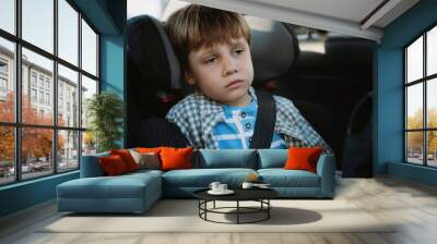 Little boy feeling sick travelling by car sitting in child seat fastened with belt Wall mural