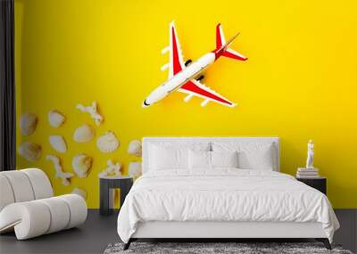 On a yellow background, a model aircraft is close to sea corals and shells.  Space for copy text.  Flat lay.  Selling online tickets, booking tours for travel.  Close-up. Wall mural