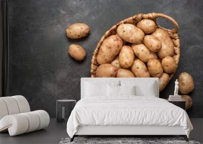 Young potatoes. Fresh potatoes in a basket on a dark background, vertical. Top view. Wall mural